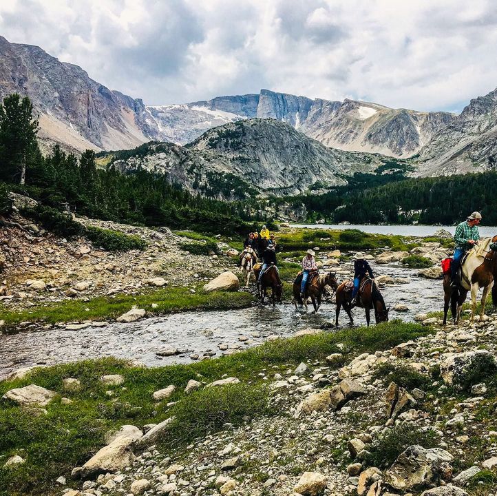 A group of people are riding horses across a river.