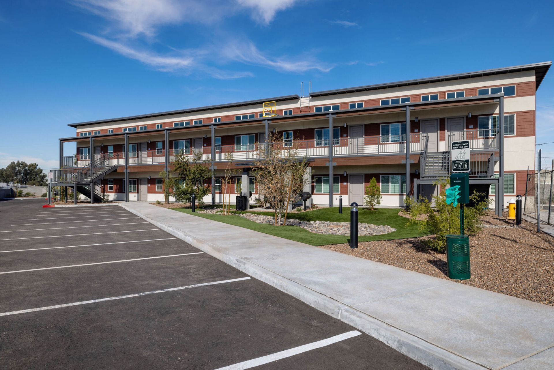 Exterior view of a multi-story apartment building with parking area and landscaping.