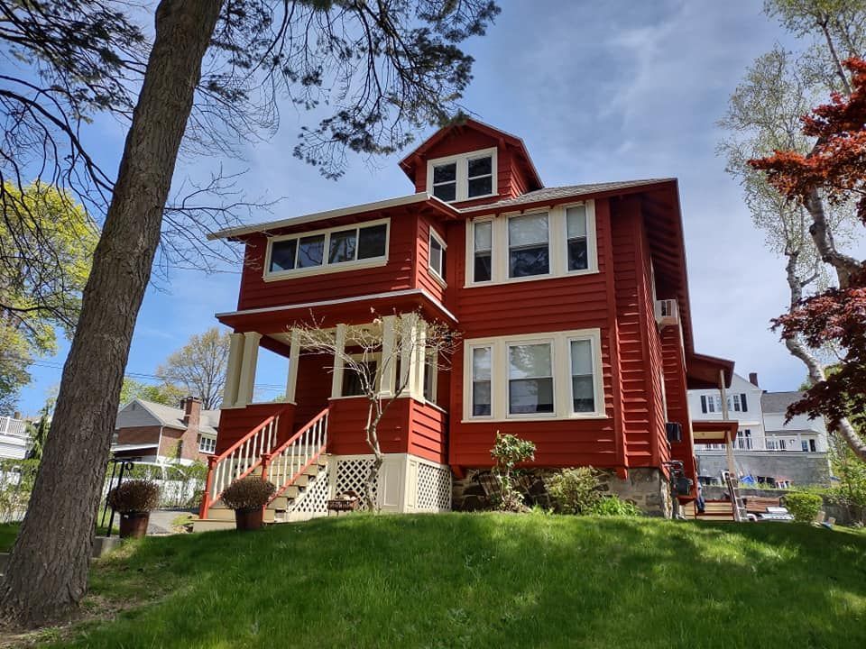 A large red house sits on top of a grassy hill