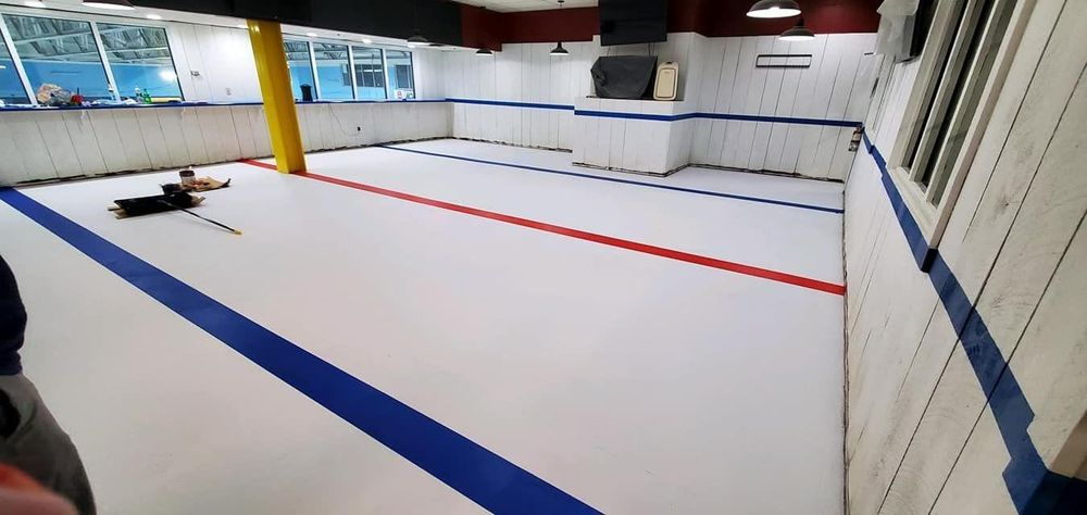 A person is laying on the floor of a wrestling mat in a gym.