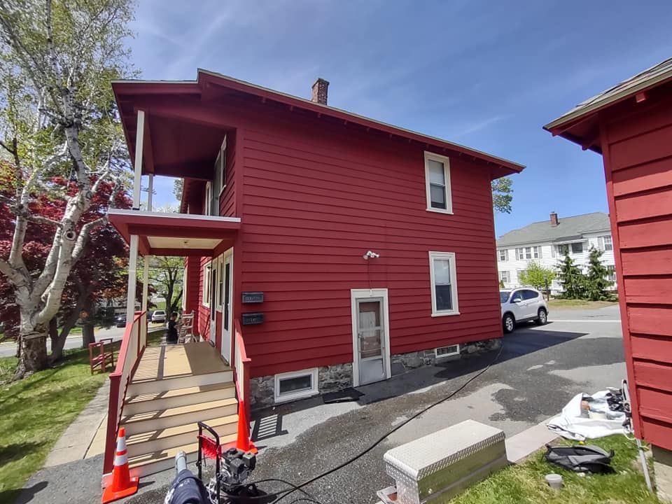 A red house with a white car parked in front of it.