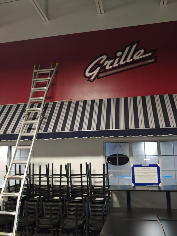 A ladder is leaning against a red wall that says grille