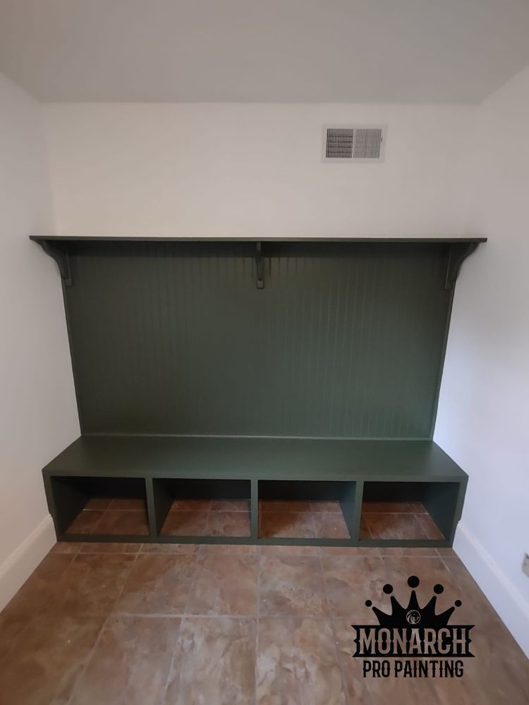 A mud room with a green bench and shelves.