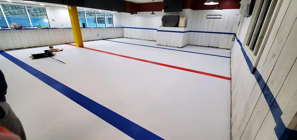 A person is laying on the floor of a gym with a blue and red stripe on the floor.