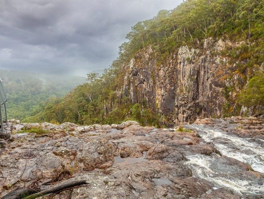 A River Flowing Through A Lush Green Forest Next To A Rocky Cliff — Ballina Demolitions In Alstonville, NSW