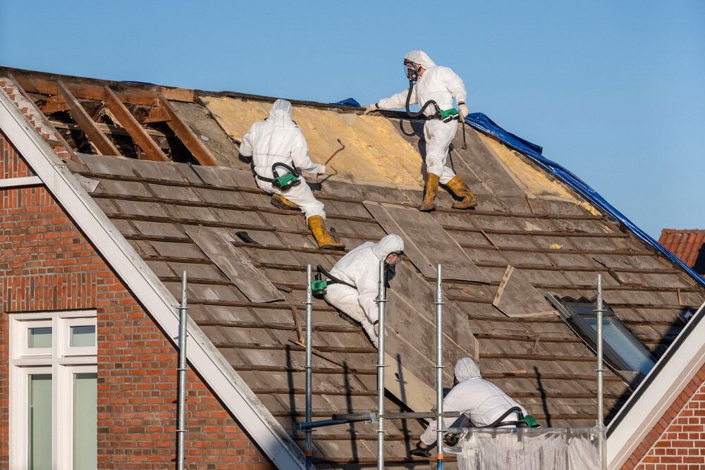 A Group Of People In Protective Suits Are Working On A Roof — Ballina Demolitions In Grafton, NSW