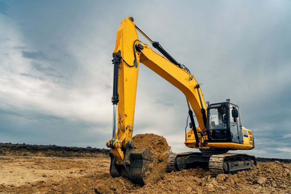 A Yellow Excavator Is Digging A Hole In A Dirt Field — Ballina Demolitions In East Wardell, NSW