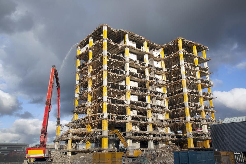 A Large Building Is Being Demolished With A Crane In The Foreground — Ballina Demolitions In Byron Bay, NSW