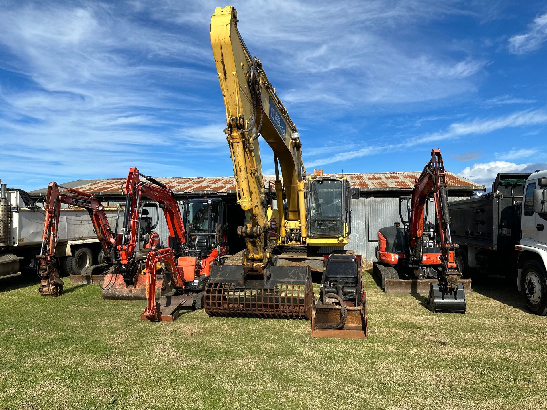 A Group Of Construction Vehicles Are Parked In A Grassy Field — Ballina Demolitions In East Wardell, NSW
