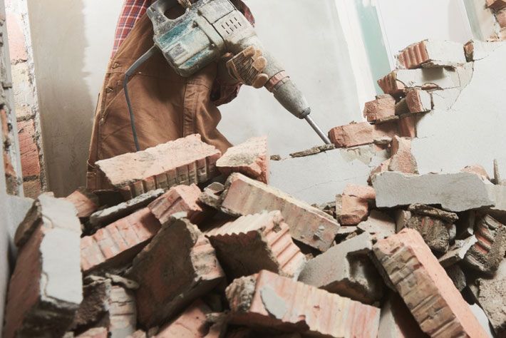 A Person Is Using A Hammer To Break Bricks In A Room — Ballina Demolitions In Yamba, NSW