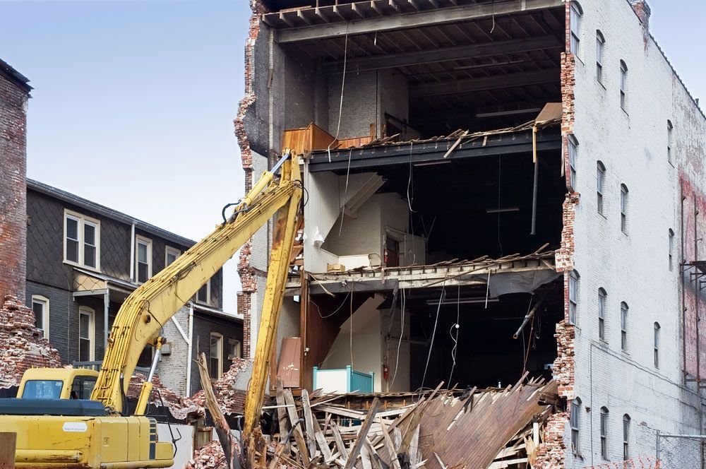 A Large Yellow Excavator Is Demolishing A Building — Ballina Demolitions In Goonellabah, NSW