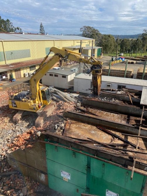 A Large Yellow Excavator Is Demolishing A Building — Ballina Demolitions In East Wardell, NSW