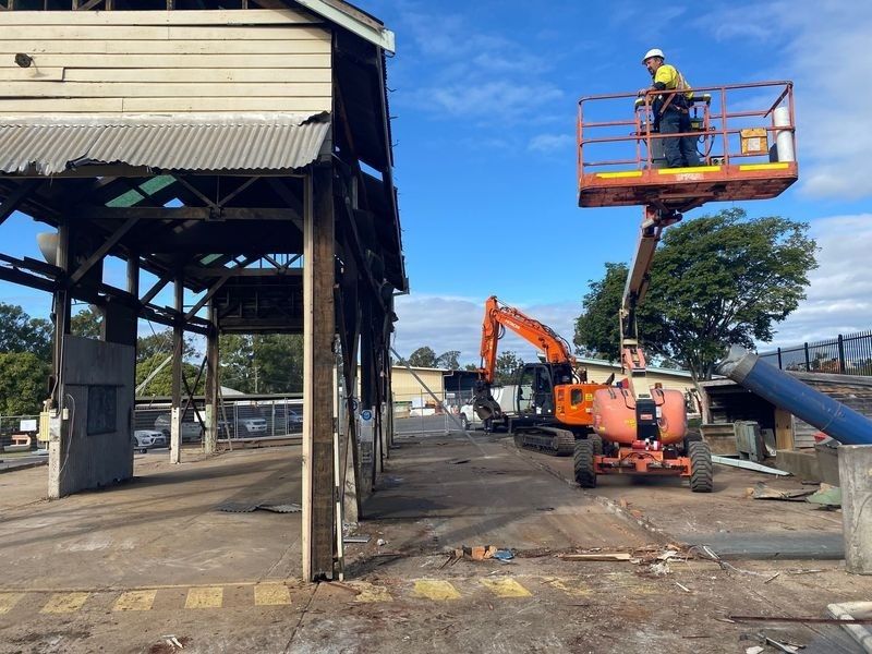 A Man Is Standing On A Lift In Front Of A Building — Ballina Demolitions In Grafton, NSW