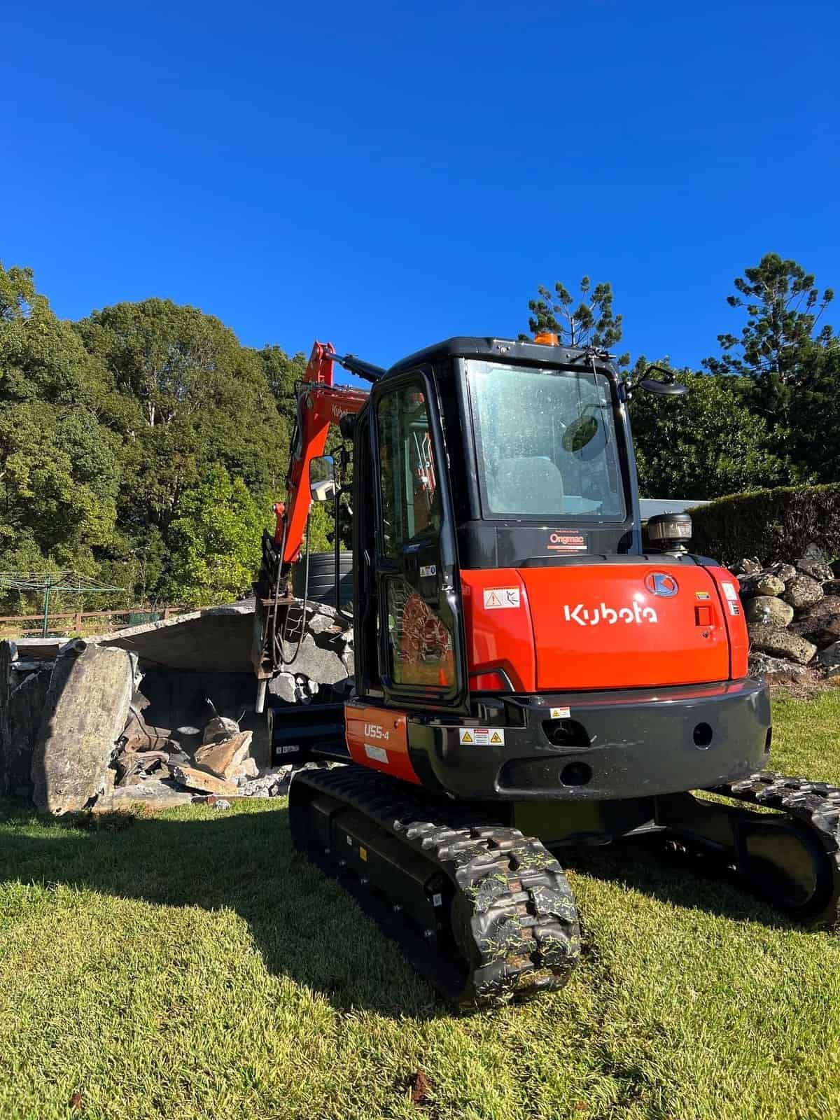 A Yellow Excavator Is Demolishing A Purple House — Ballina Demolitions In Byron Bay, NSW