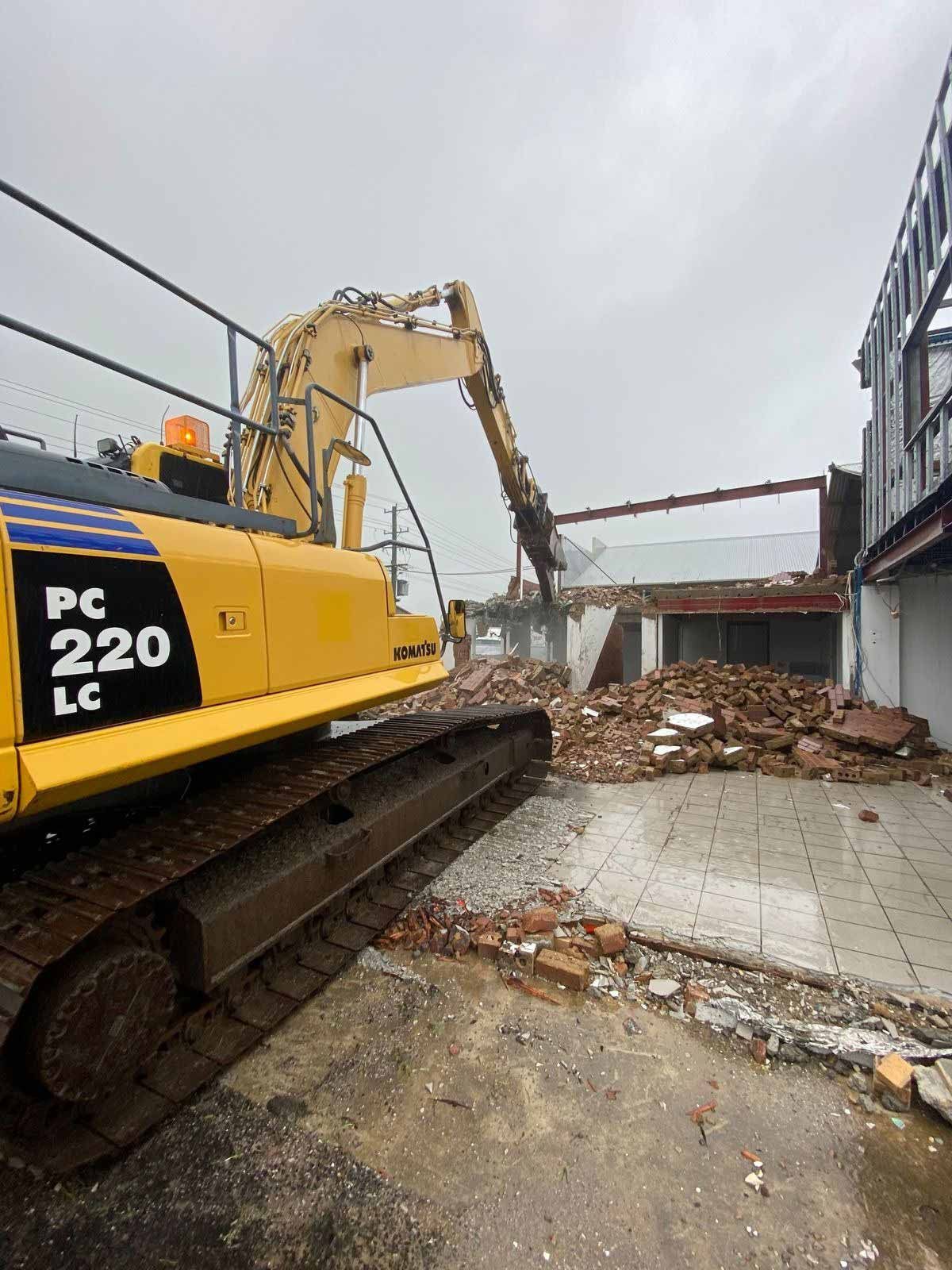 A Large Yellow Excavator Is Demolishing A Building — Ballina Demolitions In East Wardell, NSW