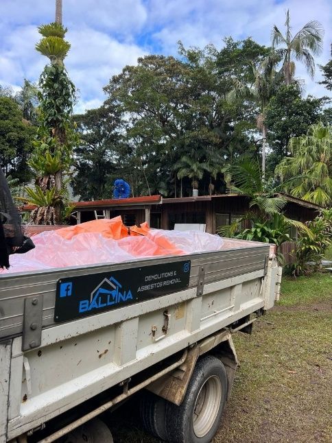 A White Dump Truck Is Sitting In A Dirt Field With Trees — Ballina Demolitions In Grafton, NSW