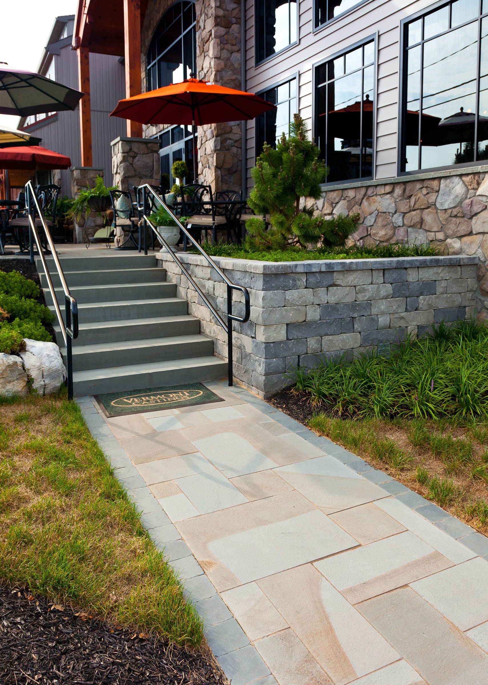 A stone walkway leading up to a building with stairs and umbrellas.