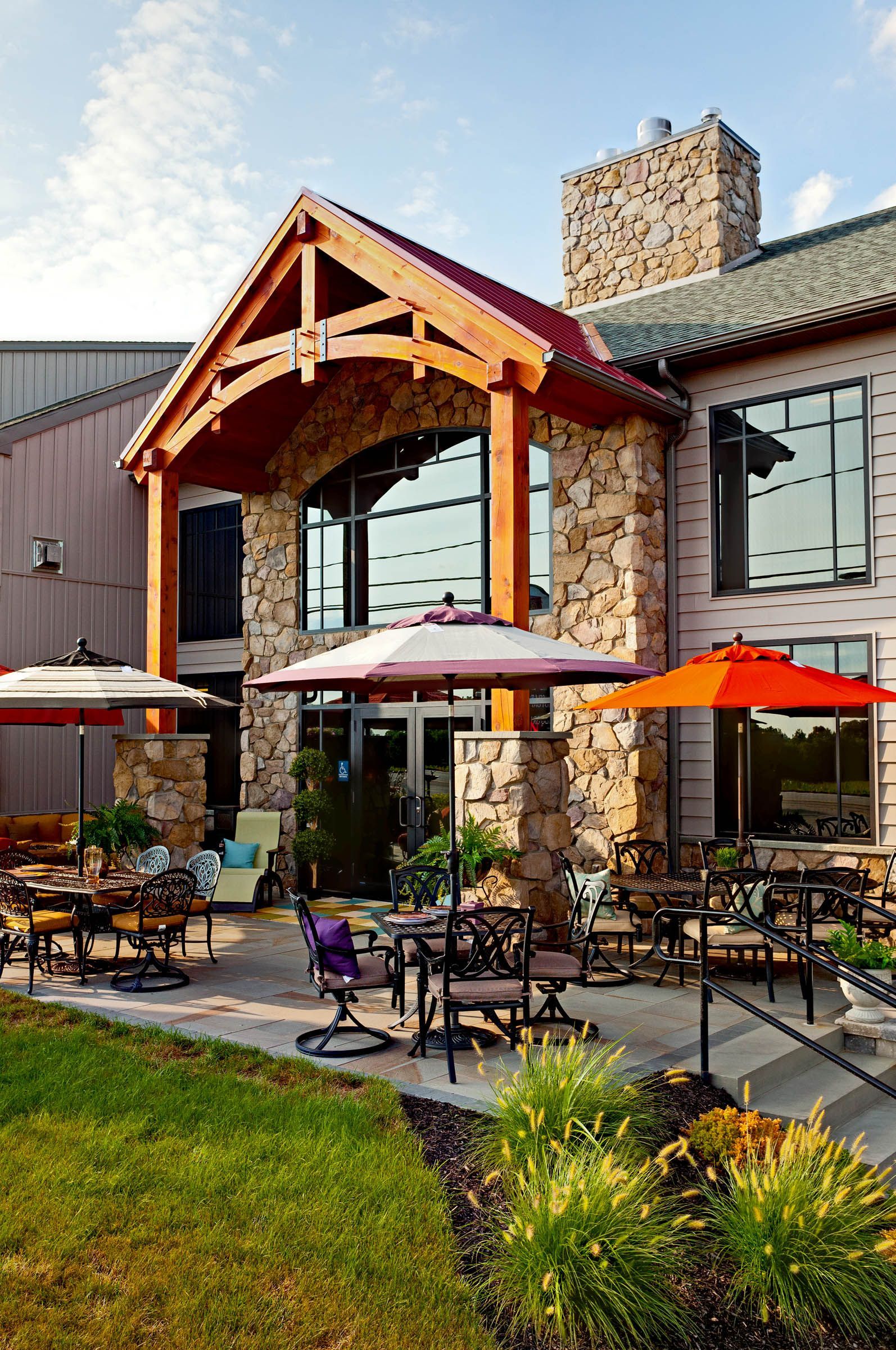 A large stone building with tables and chairs and umbrellas in front of it.