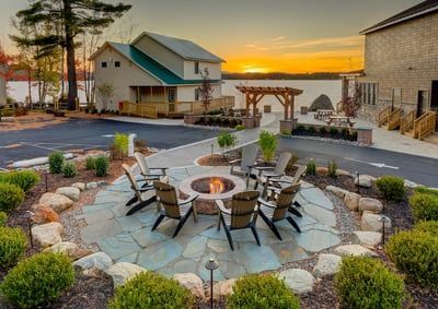 There is a fire pit in the middle of the patio with chairs around it.