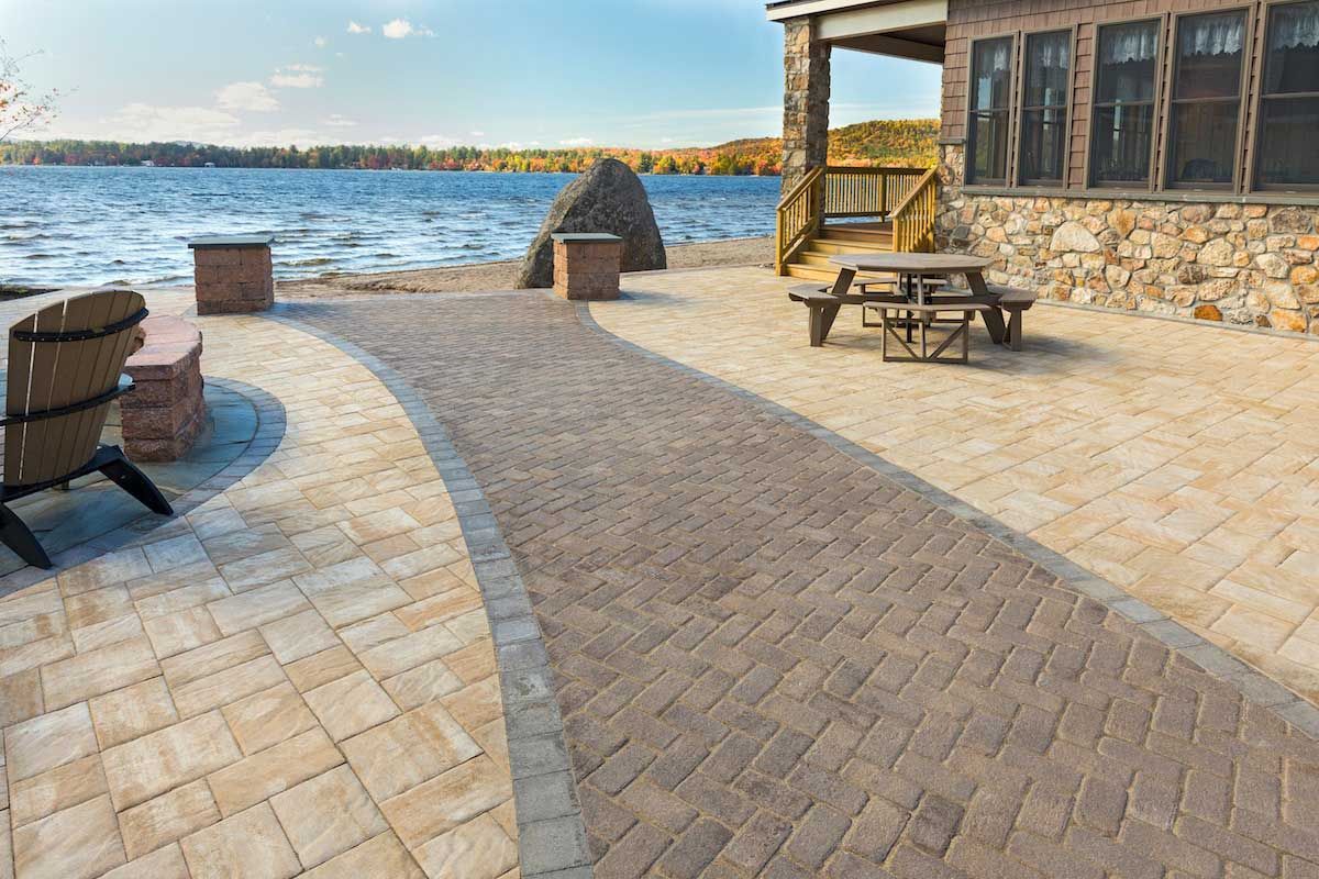 A patio with a picnic table and chairs next to a lake.