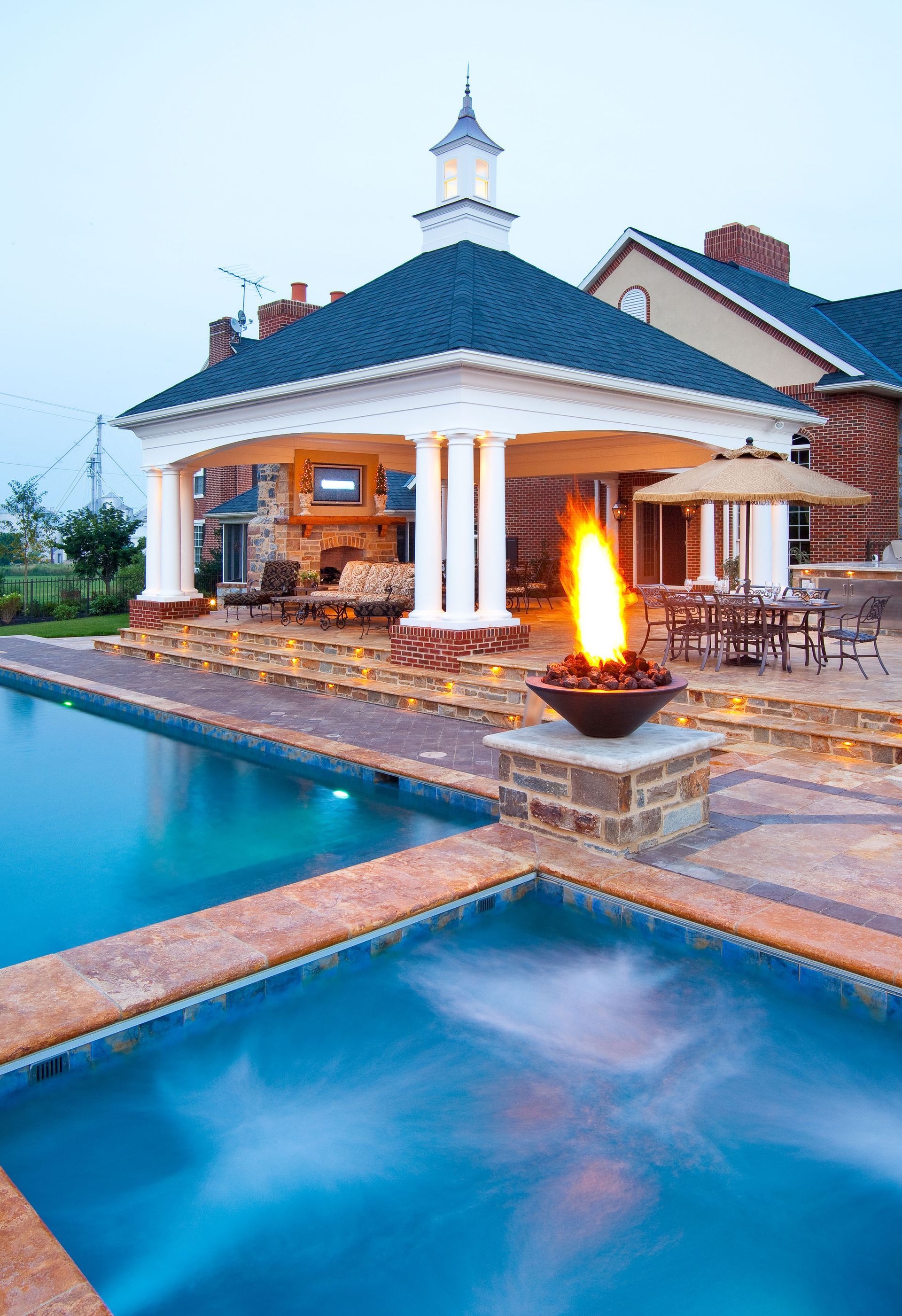 A large swimming pool with a fire pit in the middle