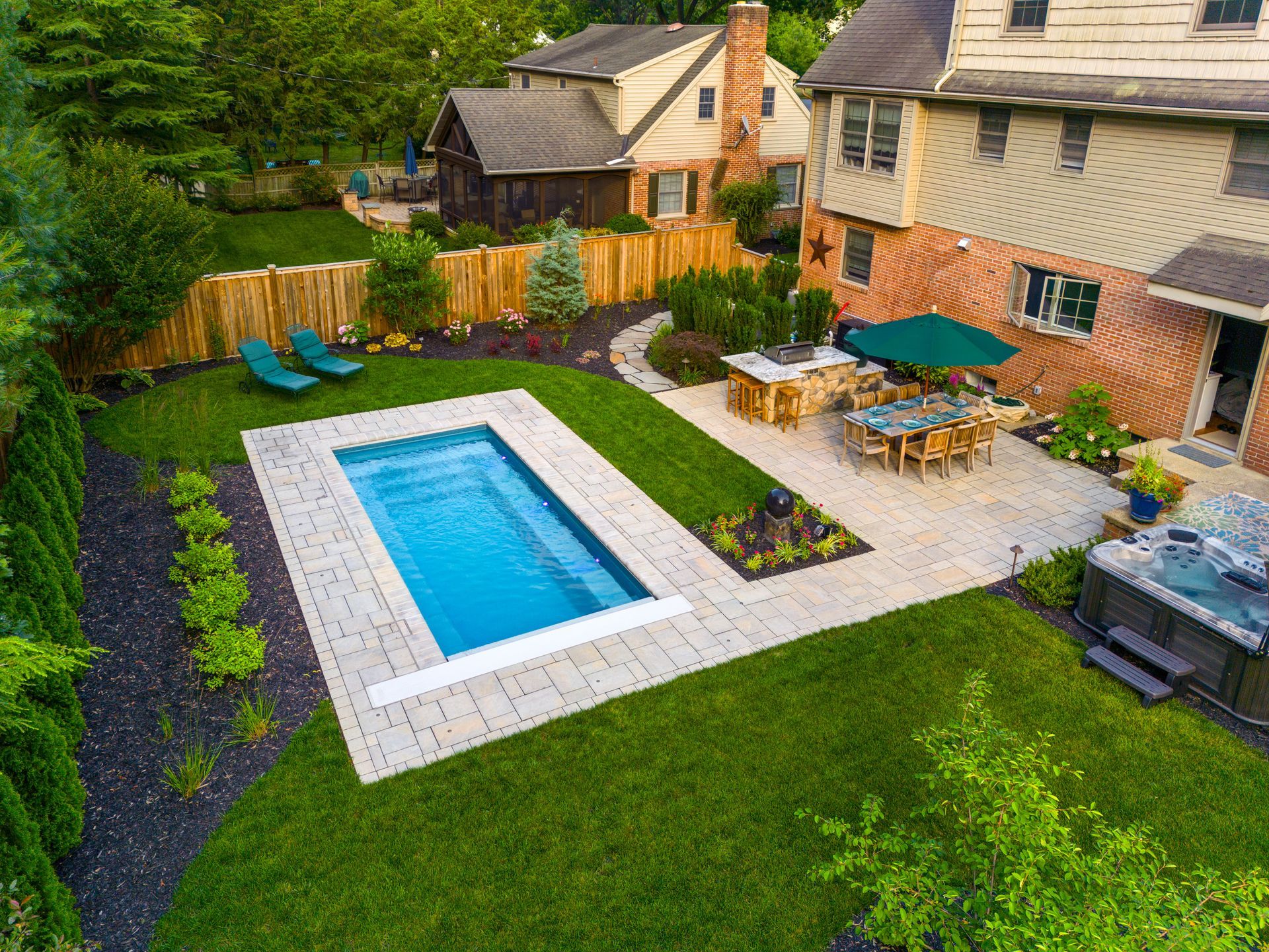 An aerial view of a backyard with a large swimming pool and a hot tub.