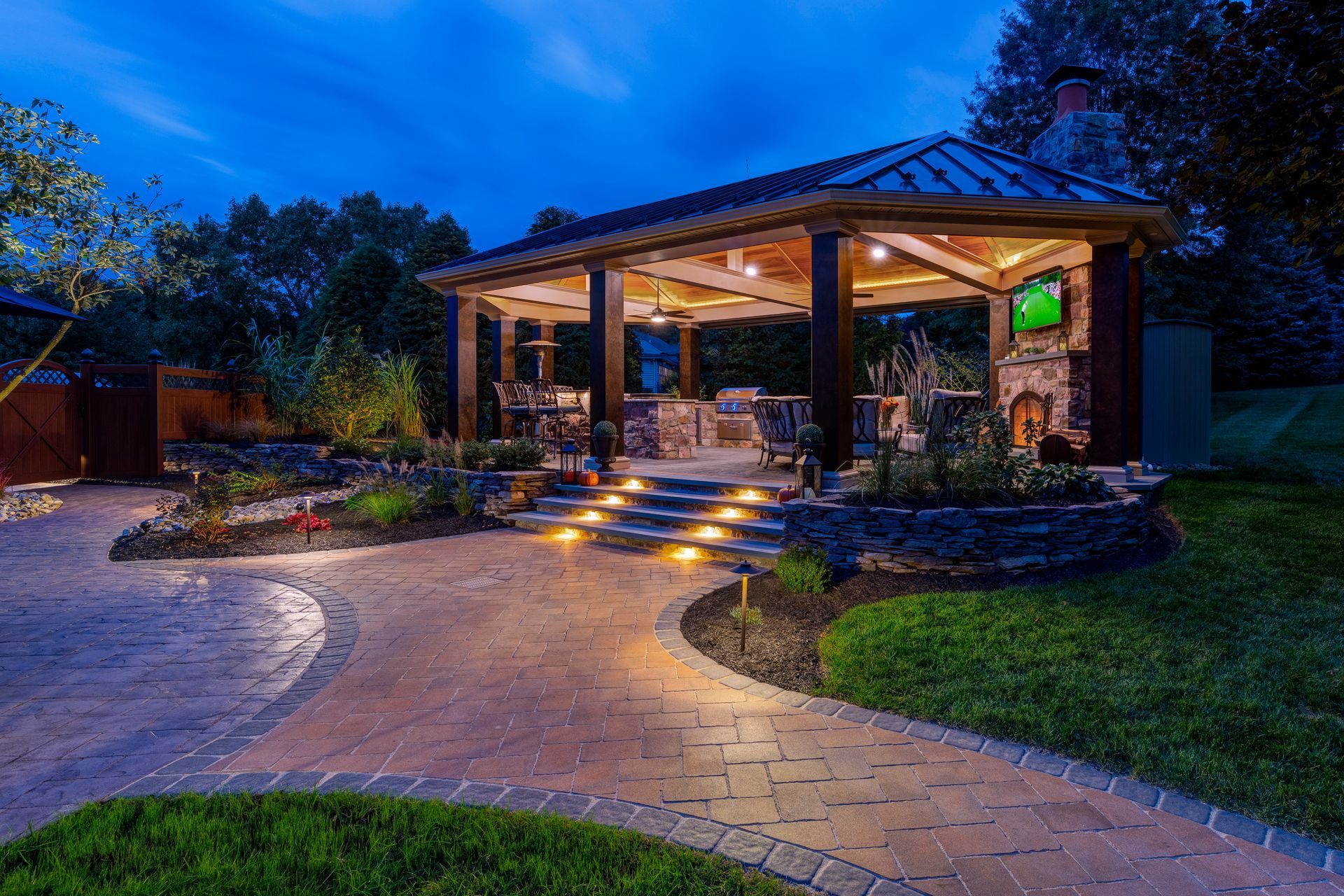 A gazebo is lit up at night in a backyard.