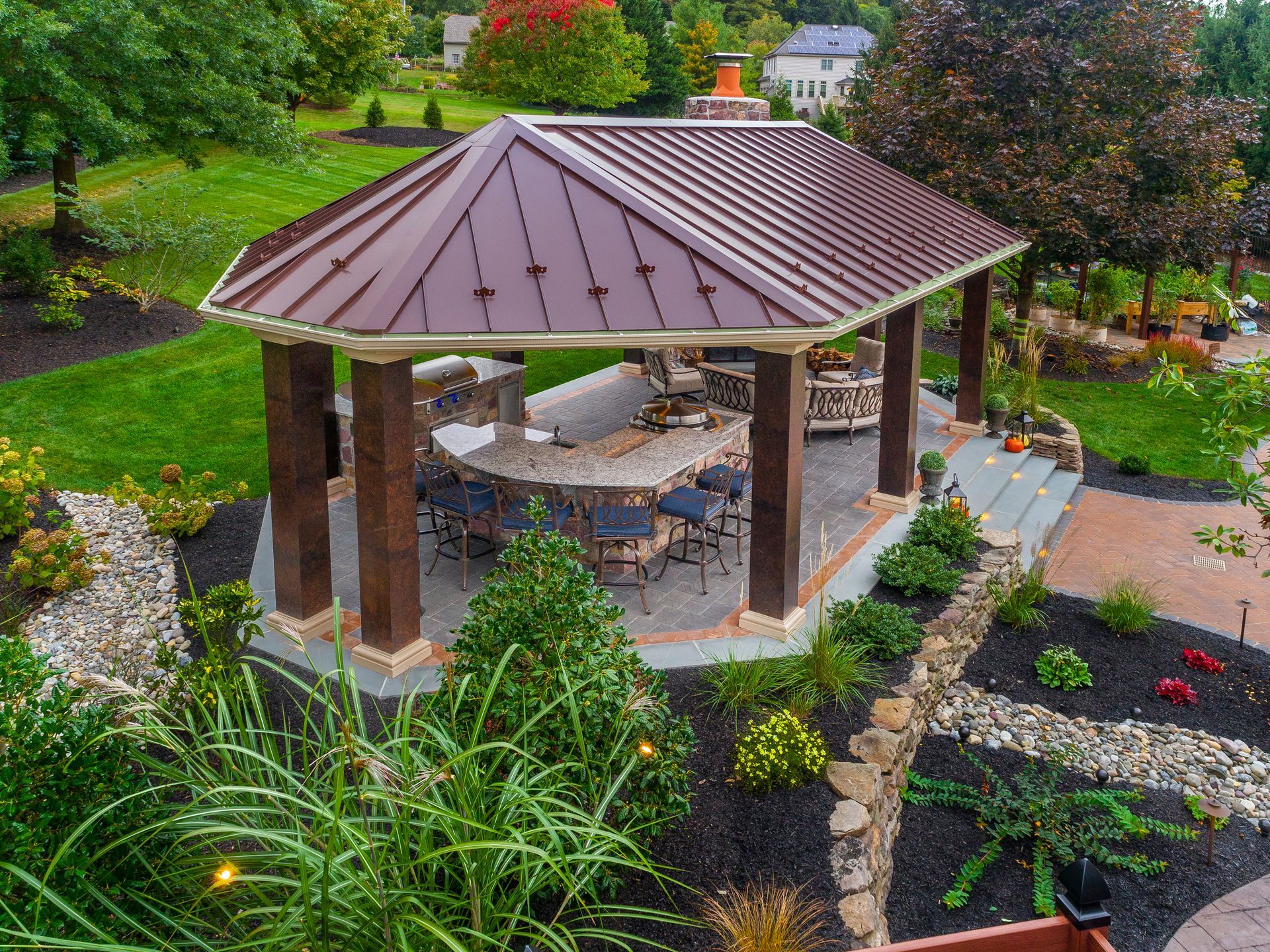 An aerial view of a gazebo with a table and chairs in a garden.