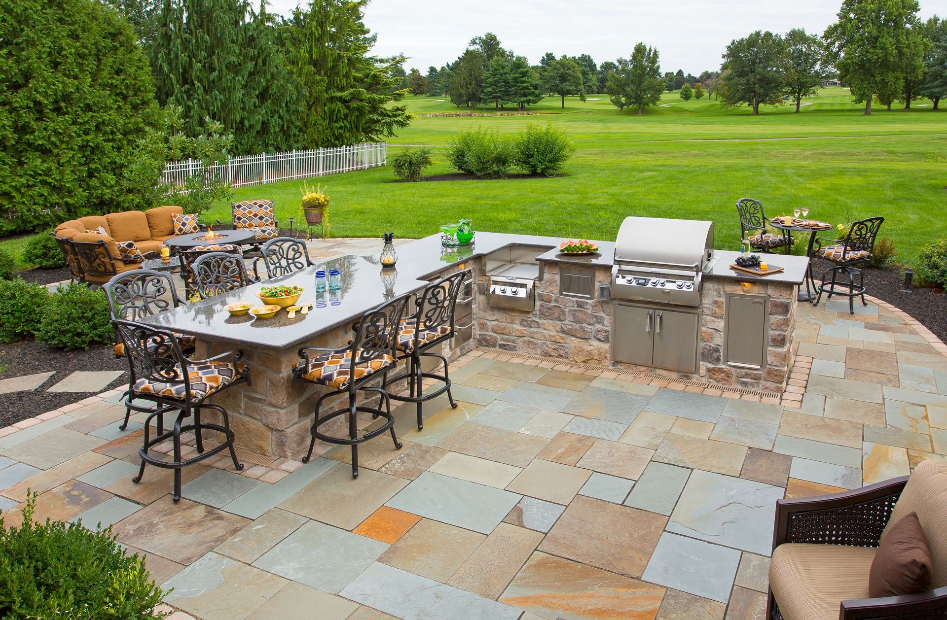 A patio with a table and chairs and a grill.