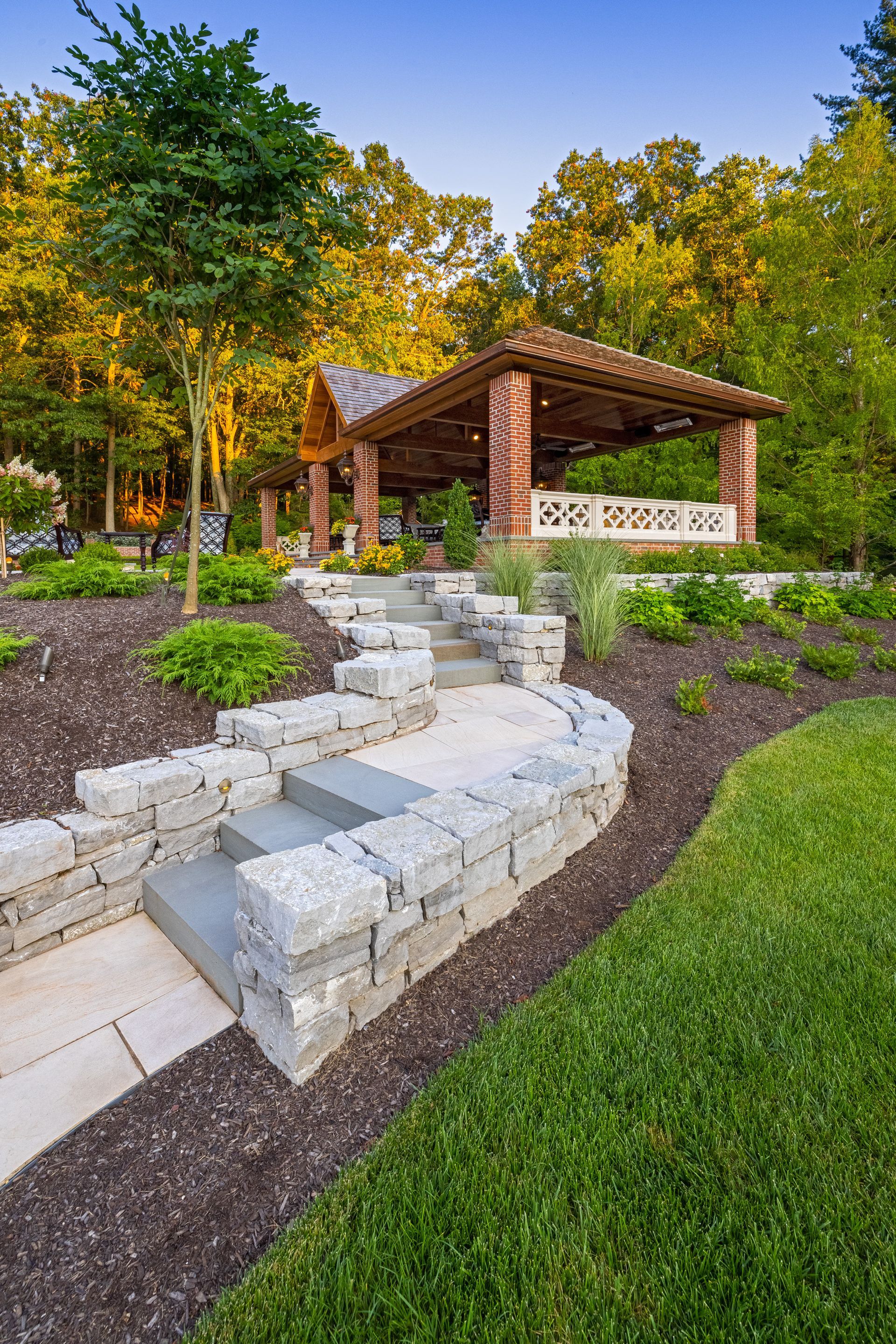 A stone walkway leading to a gazebo in a park.