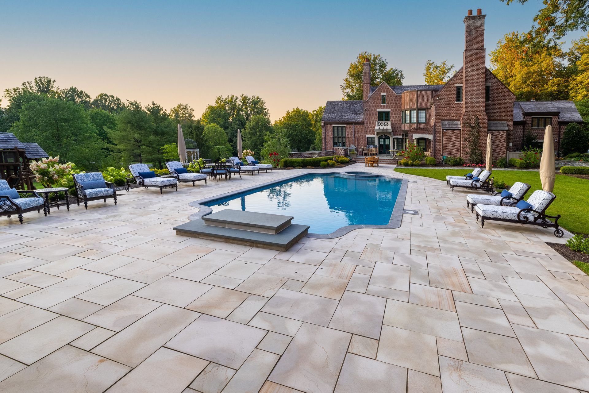 A large brick house with a large swimming pool in front of it