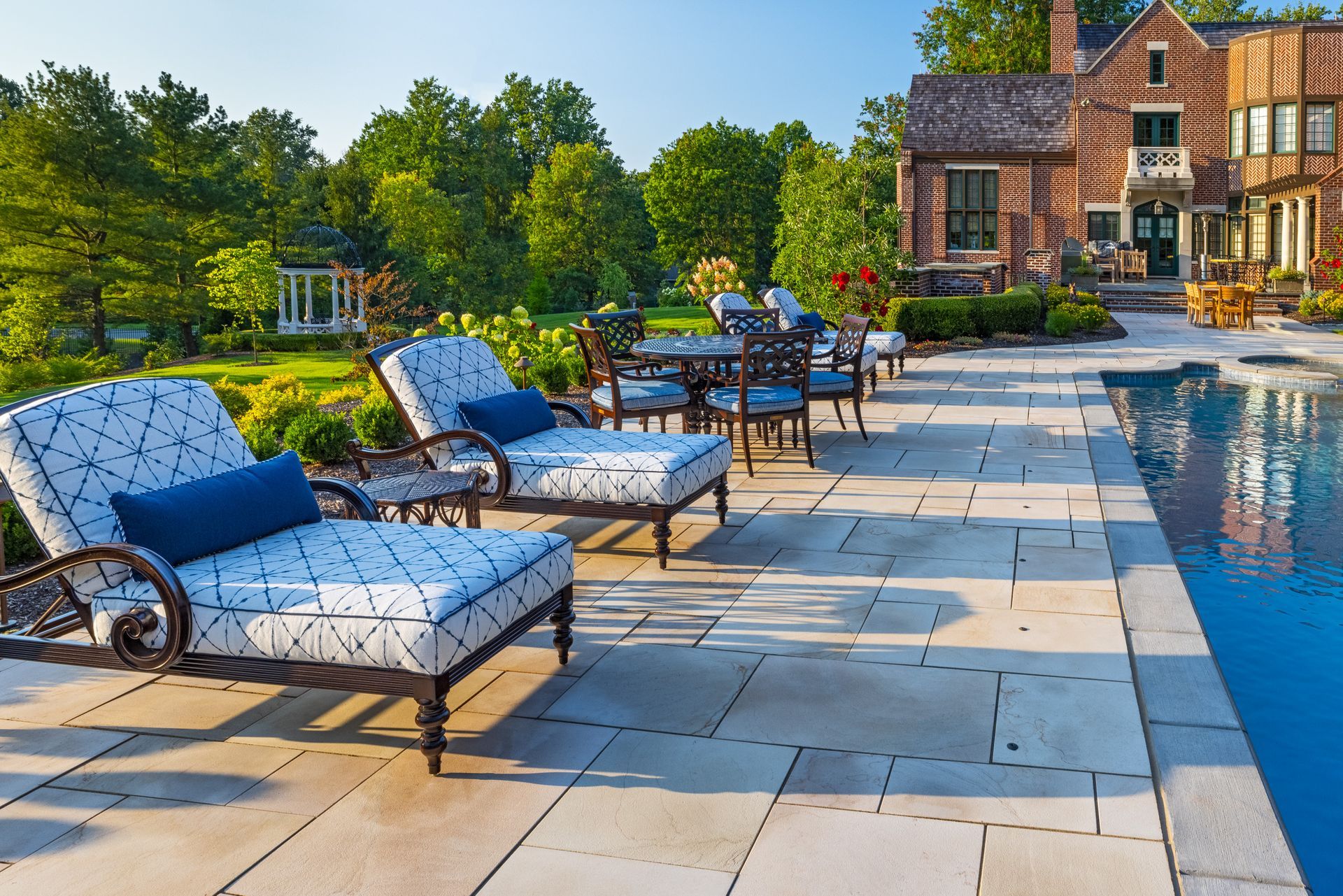 A patio with chairs and tables next to a swimming pool.