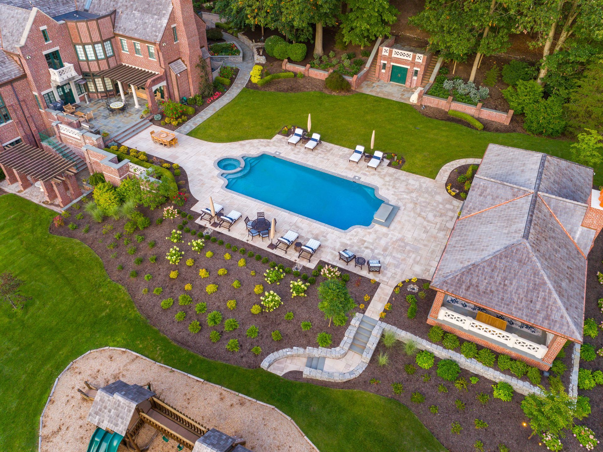 An aerial view of a large house with a large swimming pool in the backyard.
