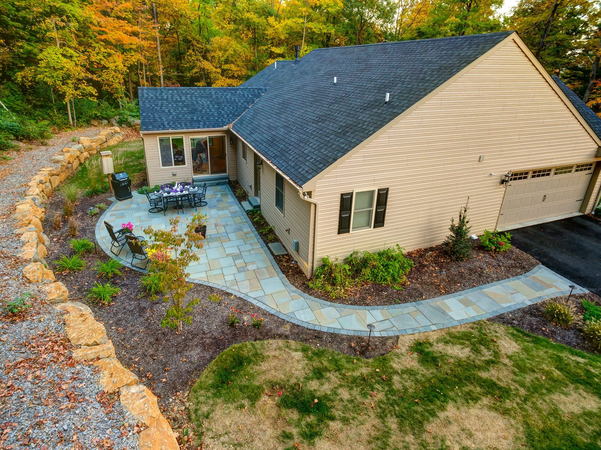 An aerial view of a house with a patio and trees in the background.