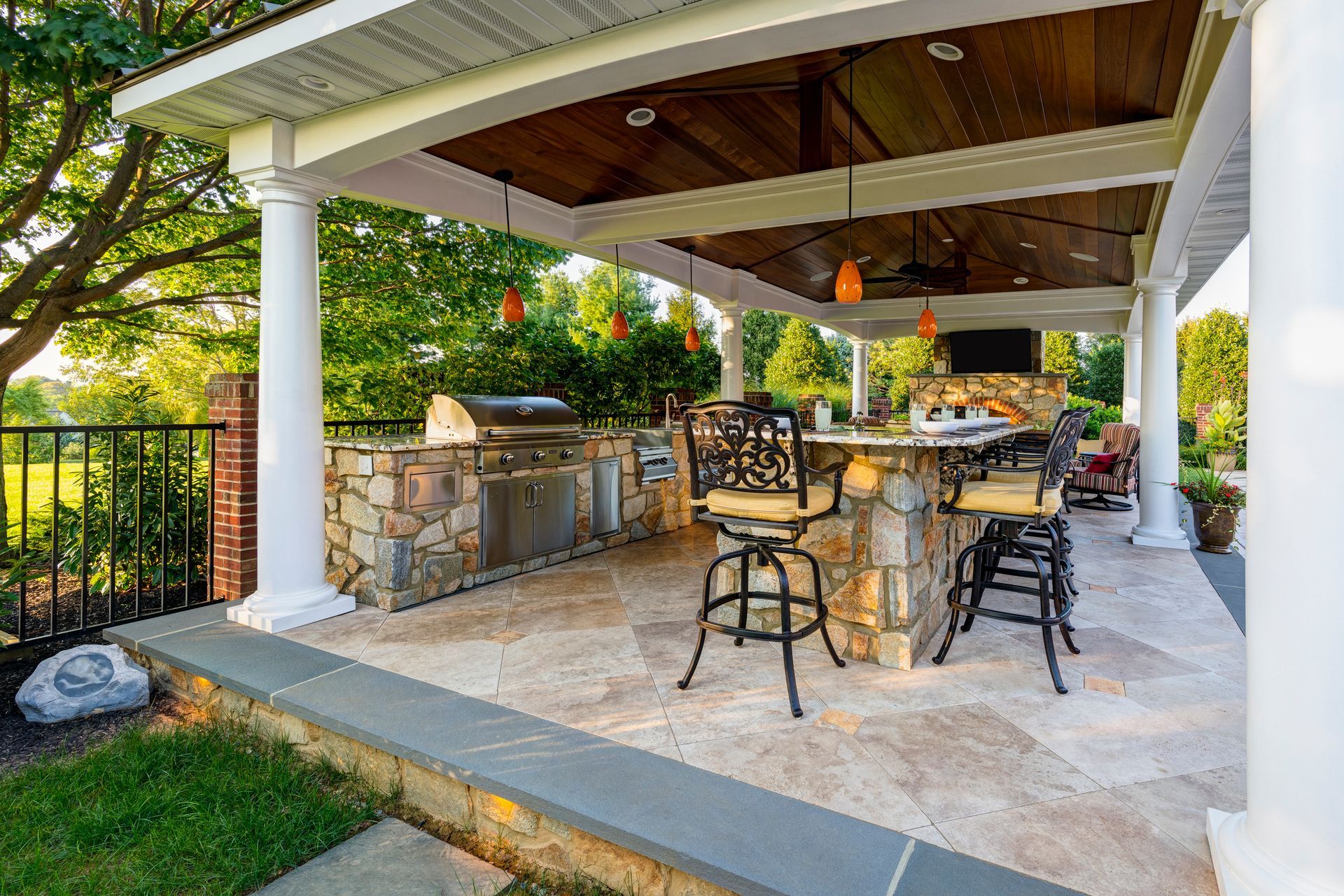 A large covered patio with a kitchen and a grill.