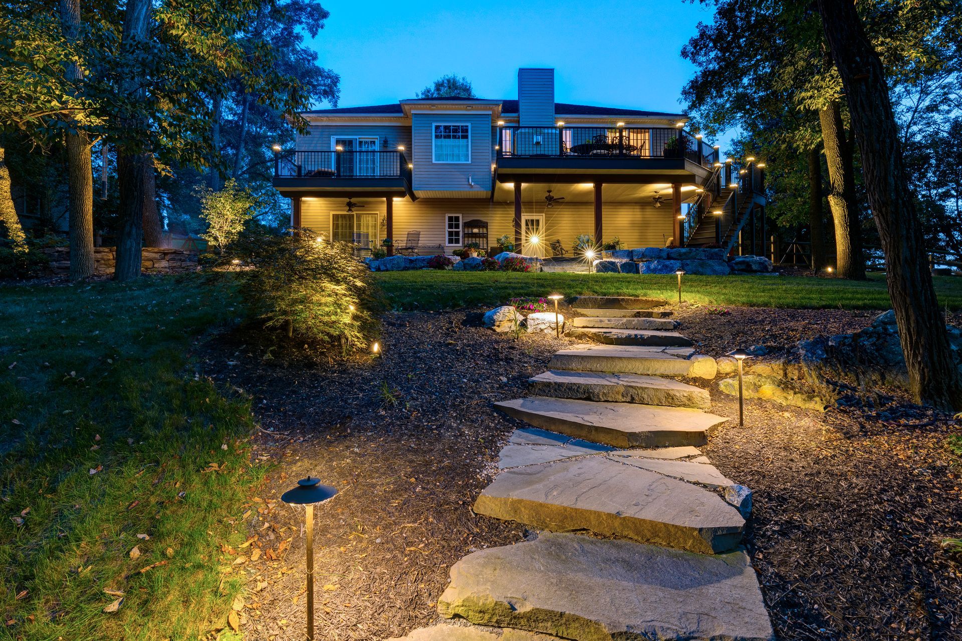 A stone walkway leading to a large house at night.