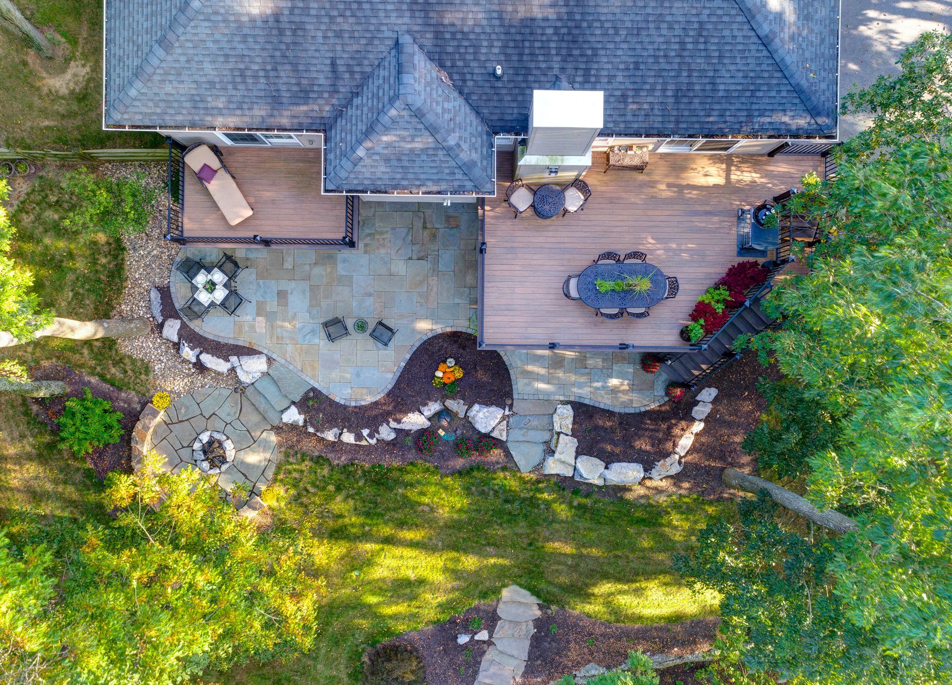 An aerial view of a house with a large deck and patio surrounded by trees.