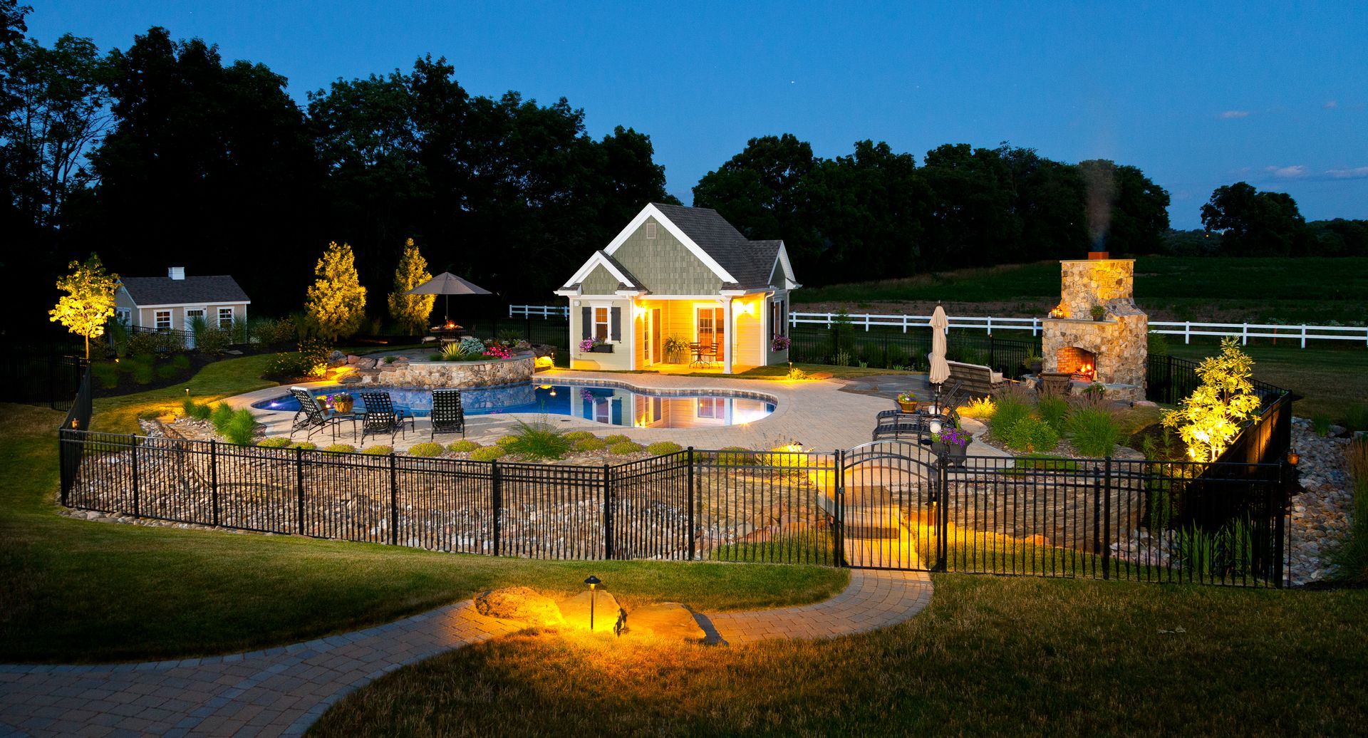 A house with a pool and a fireplace in the backyard at night.