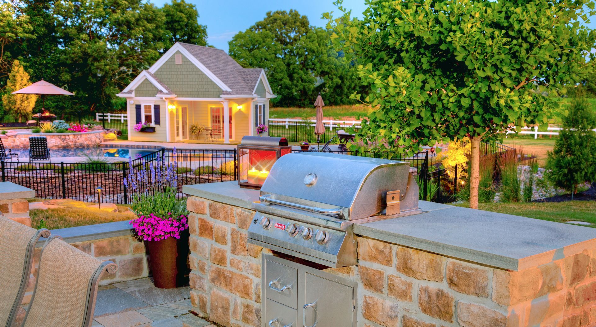 A grill is sitting on top of a brick wall in front of a house.