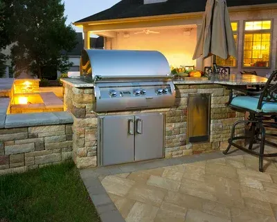 A stainless steel grill is built into a stone wall