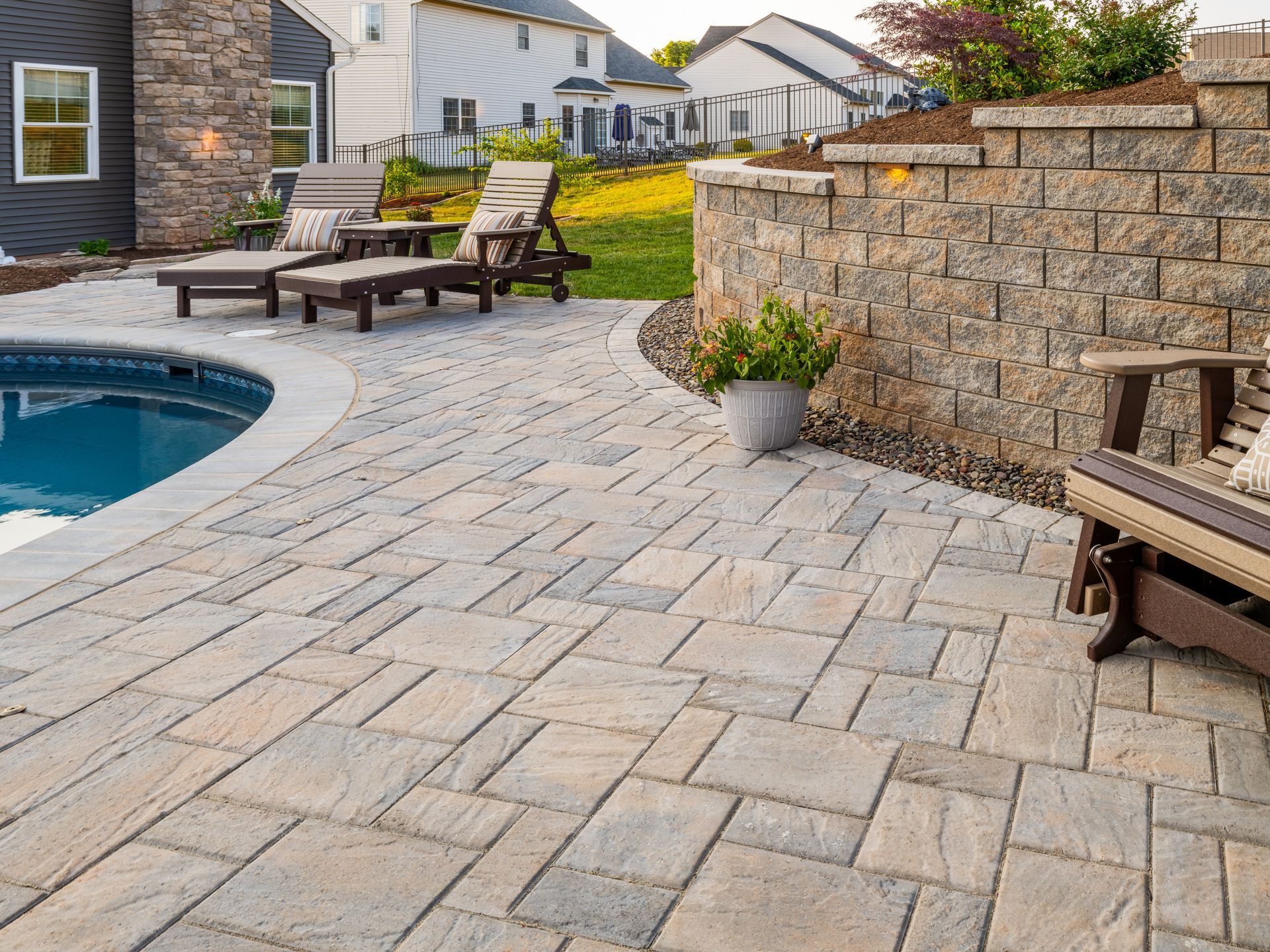 A patio with chairs and a swimming pool in the background.