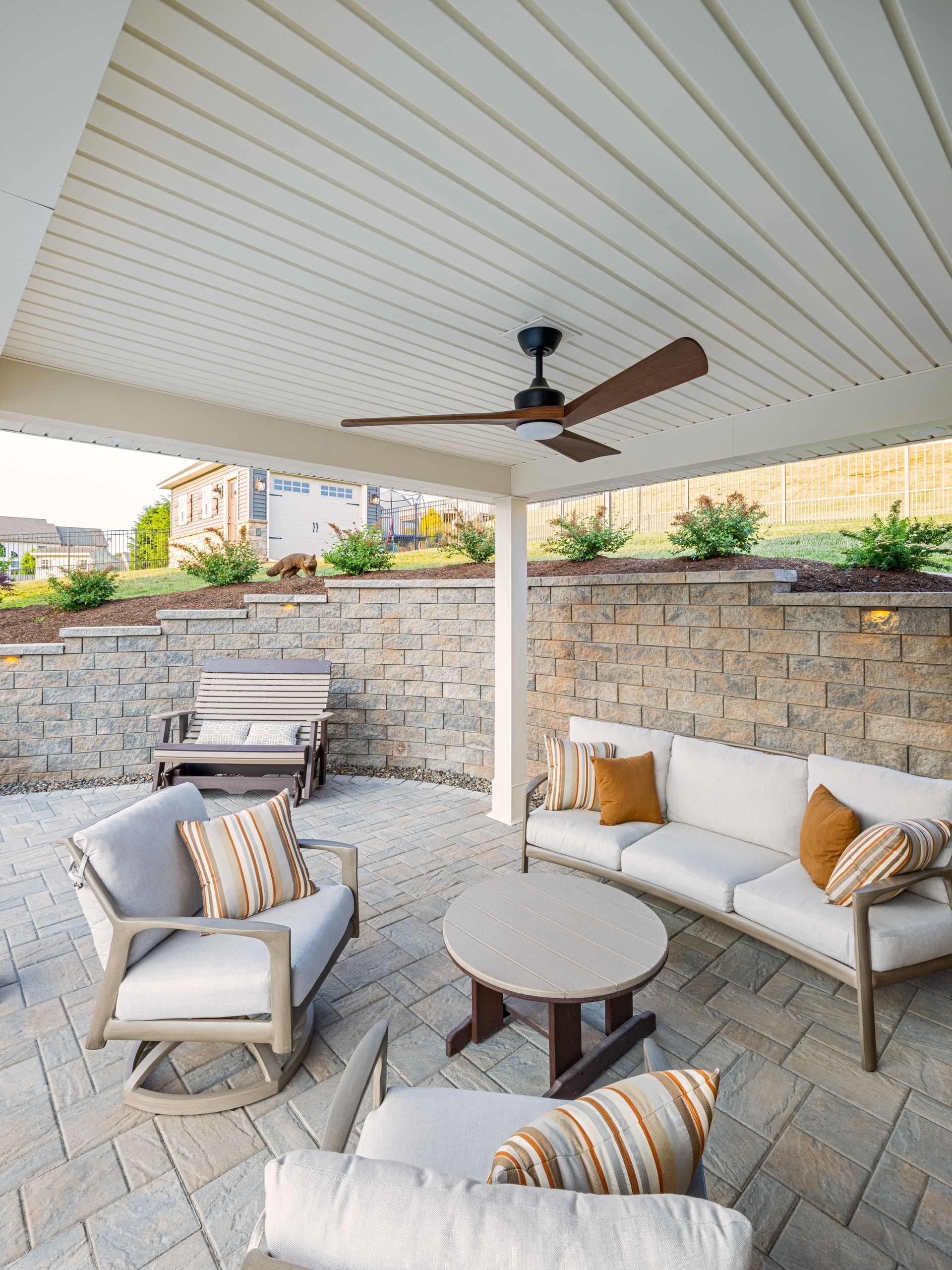A patio with a couch , chairs , a table and a ceiling fan.