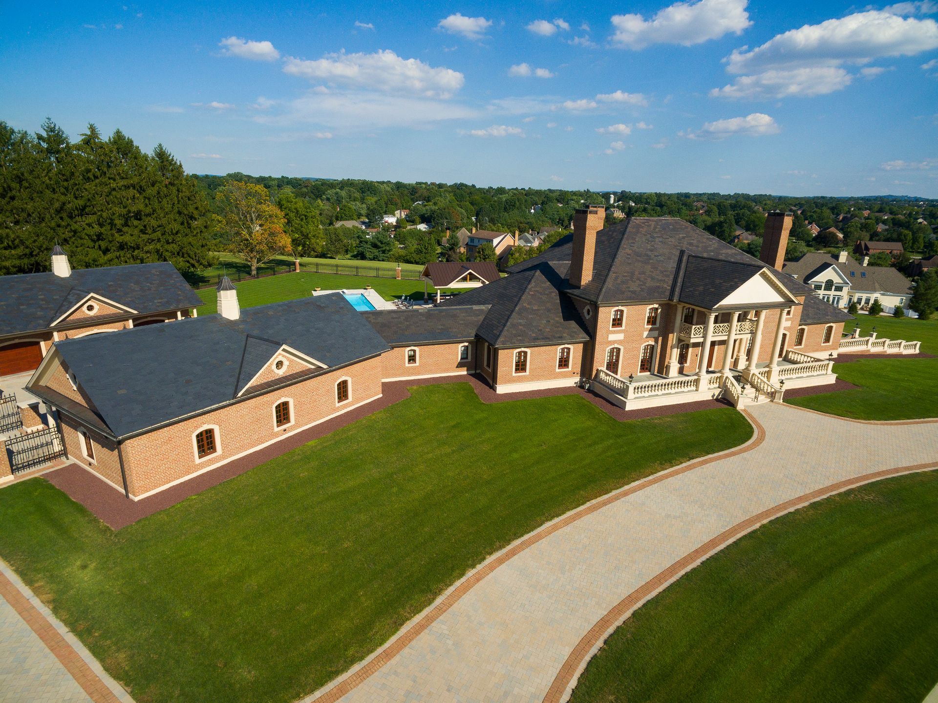 An aerial view of a large brick house with a driveway leading to it.