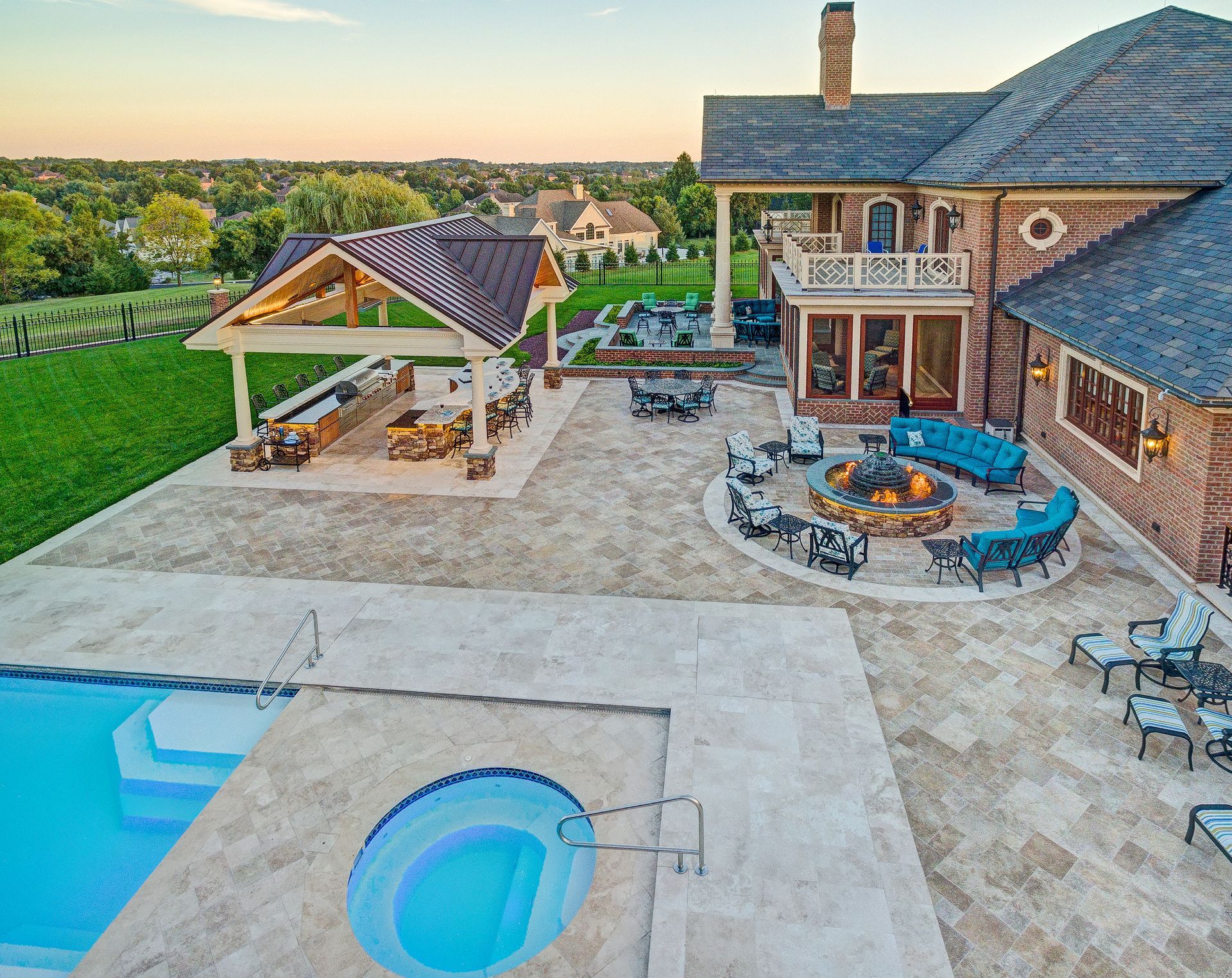 An aerial view of a large house with a swimming pool and a fire pit.