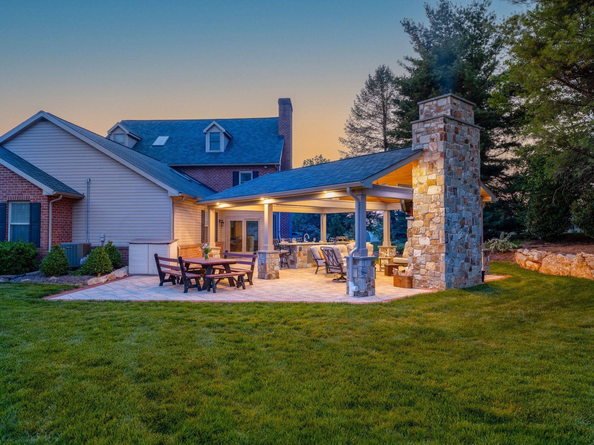 The backyard of a house with a patio area and a stone fireplace.