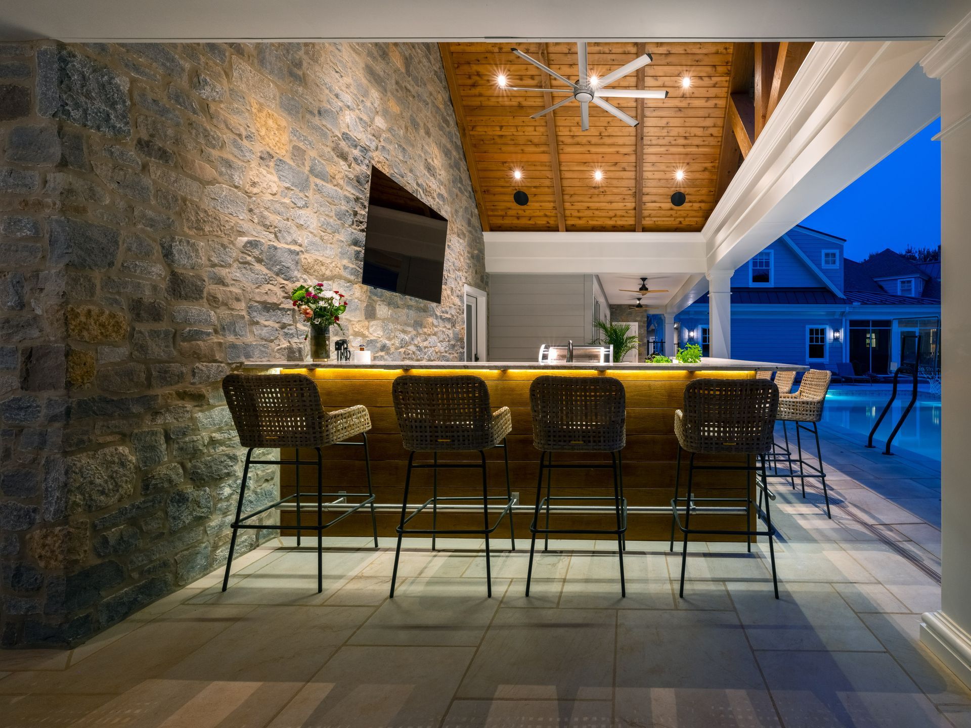 There is a bar with stools and a television on the wall.
