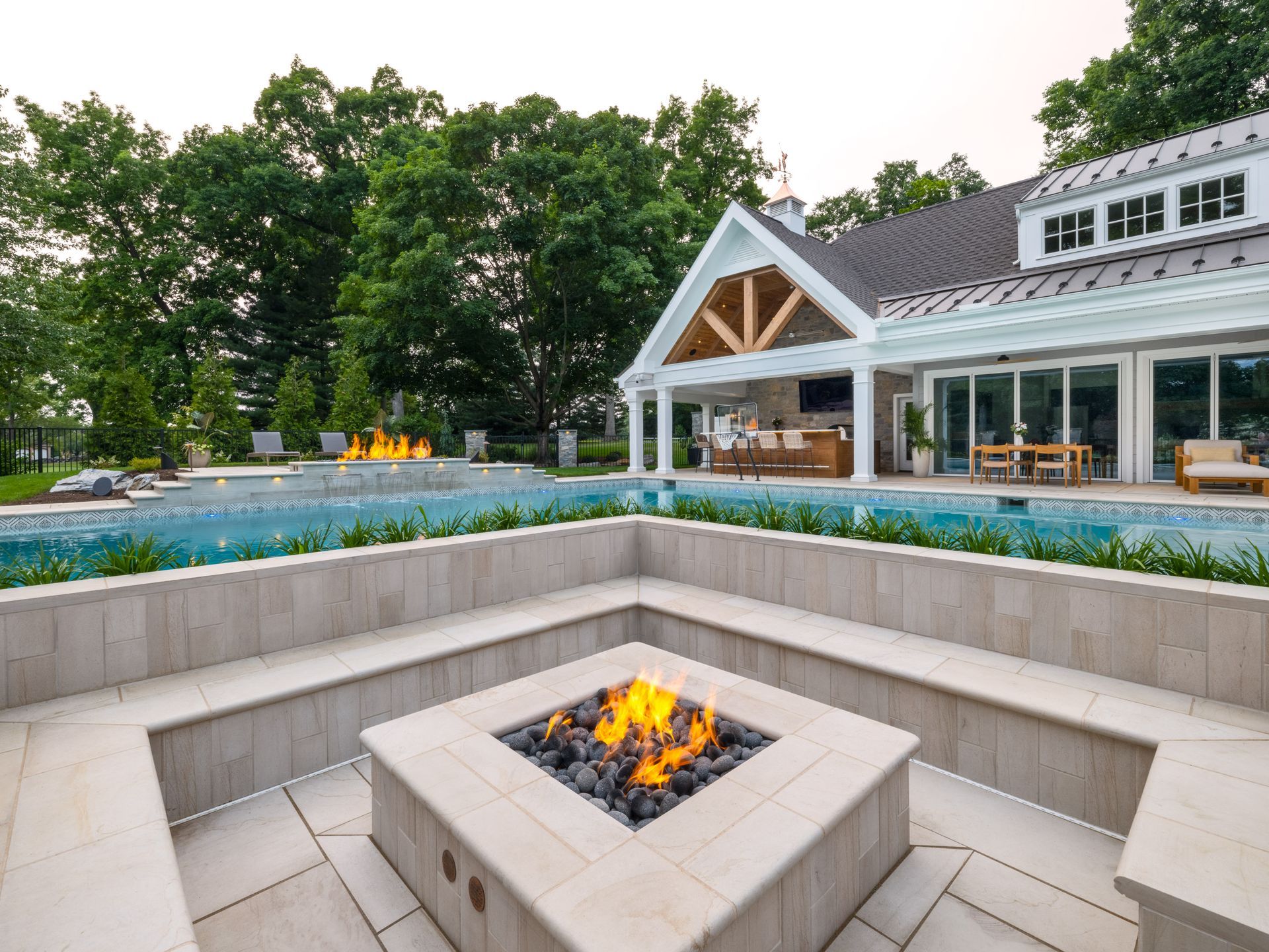 There is a fire pit in the middle of the patio in front of a large house.
