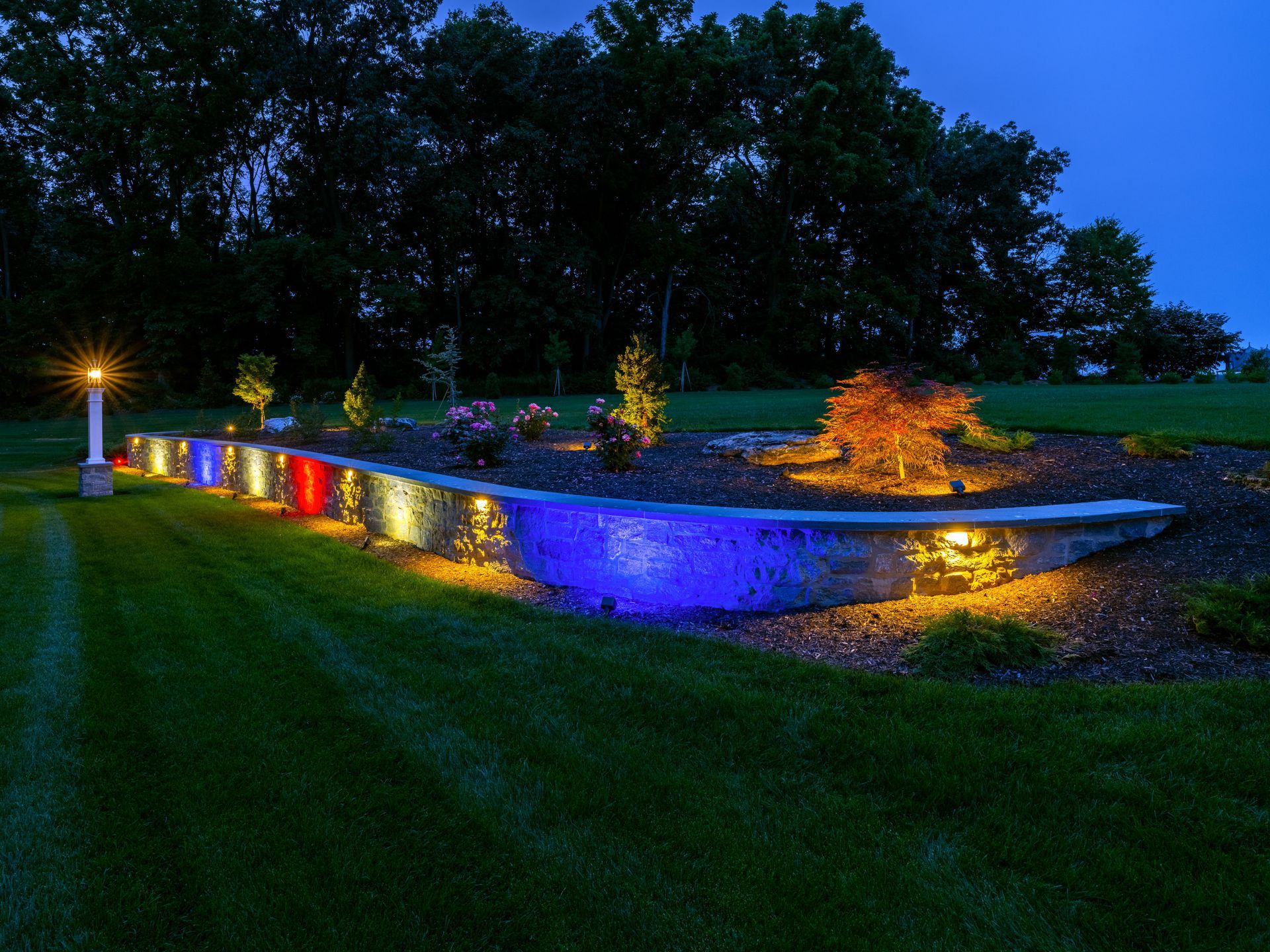 A row of lights on a wall in a yard at night.