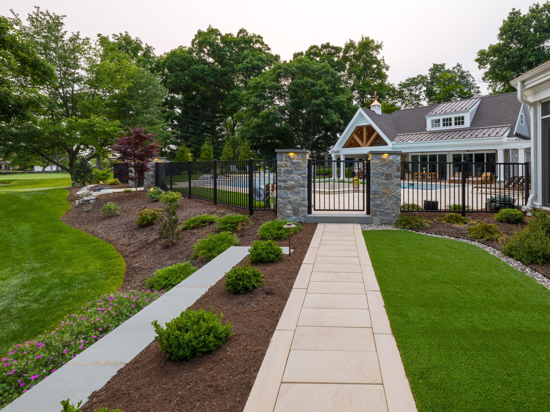A walkway leading to a house with a pool in the backyard.