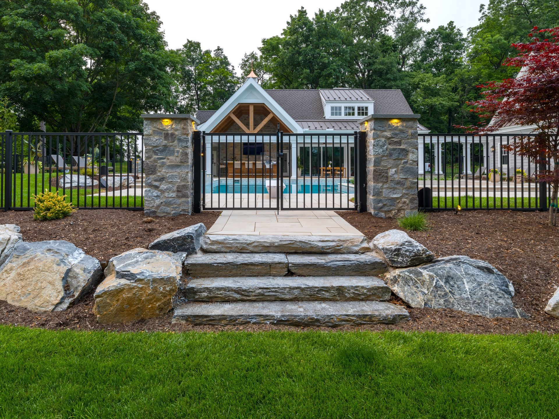 A house with a pool and stairs leading to it behind a fence.